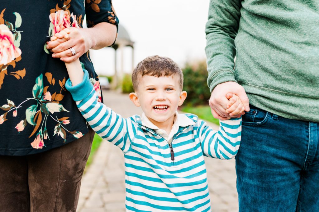 Smiling boy holding his parents hands at Glenwood Gardens